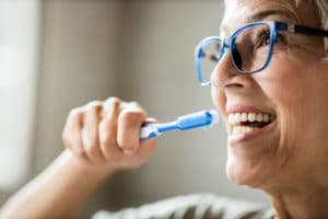 Close up of happy mature woman brushing her teeth. Copy space.
