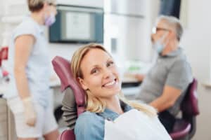 A woman smiling in a dentist's chair after getting dental implants in Sugar Land, TX